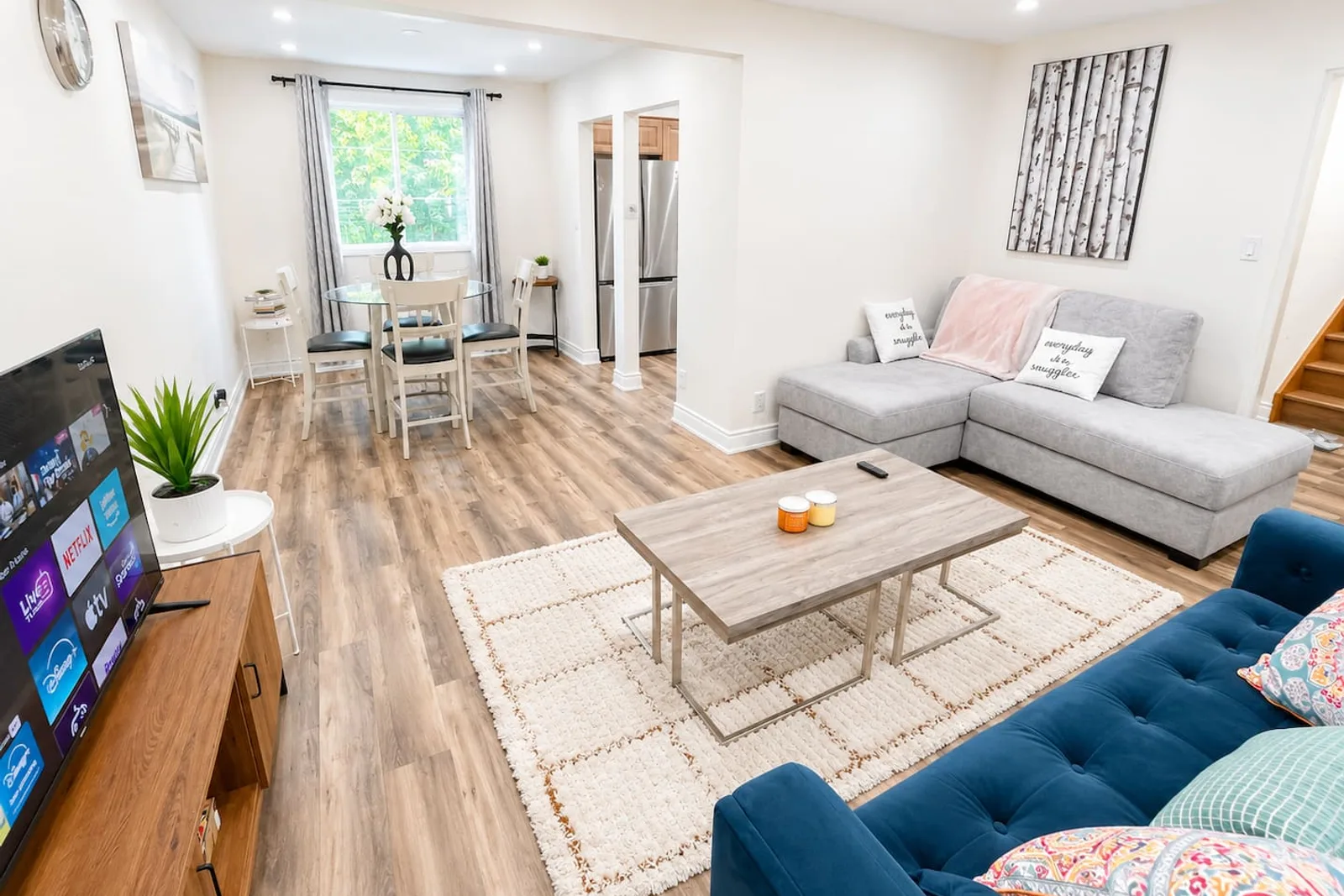 Main living room with sectional seating, a television and an open dining area